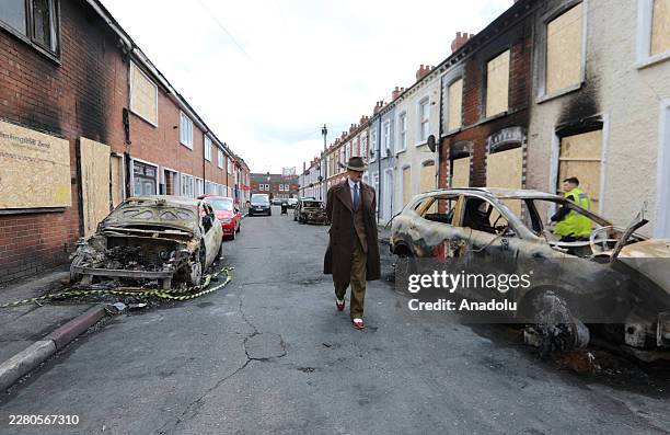 Man walks among burned cars on the street as a clean-up operation is under way after a race riots erupted in Belfast, Northern Ireland, on June 12,...