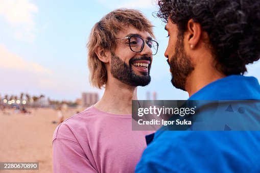 Schwules Paar genießt einen liebevollen Moment am Strand bei Sonnenuntergang Schwules Paar genießt einen liebevollen Moment am Strand bei Sonnenuntergang