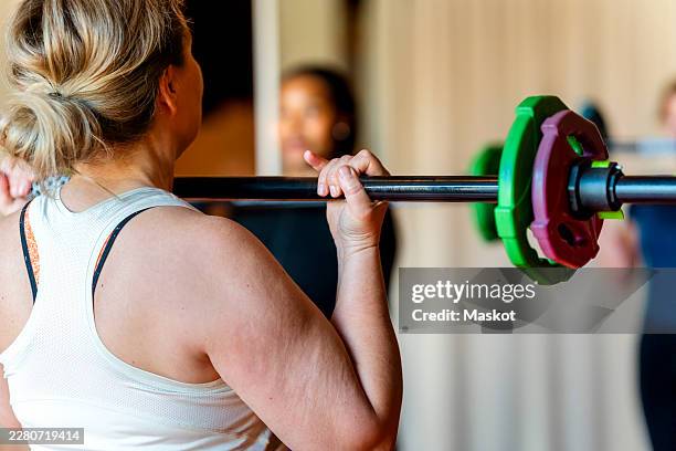 rear view of athletic woman doing strength training with barbell in gym - tyngdlyftning bildbanksfoton och bilder