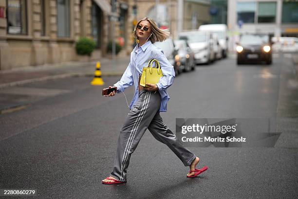 Laura Wittek is seen wearing an oversized light blue cotton shirt with button front closure from Bershka Men; gray cotton trousers with a straight...