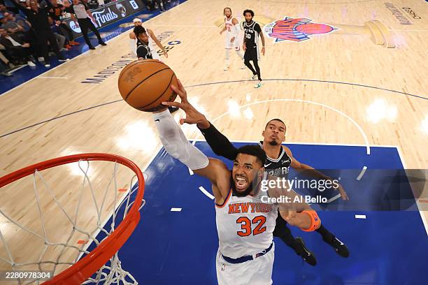 Karl-Anthony Towns of the New York Knicks attempts a shot while being fouled by Victor Wembanyama of the San Antonio Spurs during the first quarter...