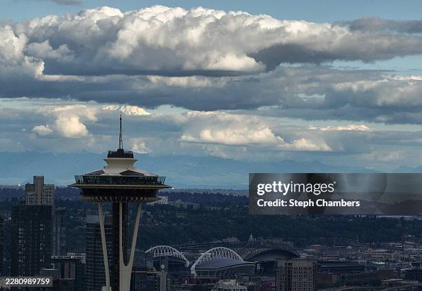 Mount Rainier peaks through the clouds as the Space Needle, painted like a giant soccer ball, stands above Seattle Stadium, temporarily renamed from...