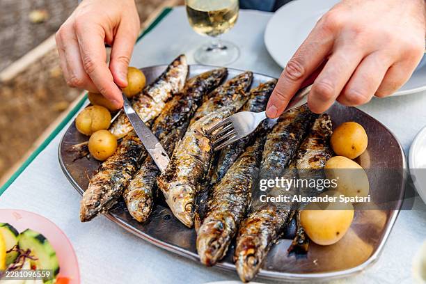 man eating grilled sardines with potatoes served at a restaurant, lisbon, portugal - sardine stock pictures, royalty-free photos & images