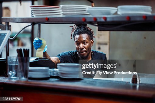 Chef afroamericano che esamina l'ordine di un cliente in cucina del ristorante Chef afroamericano che esamina l'ordine di un cliente in cucina del ristorante