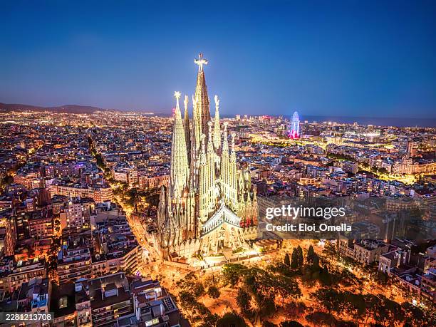 sagrada familia basilica illuminated at night in barcelona, spain, providing an aerial view of the historic architecture glowing across the expansive city skyline - sagrada família imagens e fotografias de stock