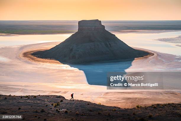 conical rock rising from a salt lake at sunrise, mangystau region, western kazakhstan - salt flat stock pictures, royalty-free photos & images