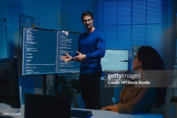 young latin software developers team meeting present source code on large monitors working late in the dark office at night. artificial intelligence, implementation details, debugging and programming. - training program stock pictures, royalty-free photos & images
