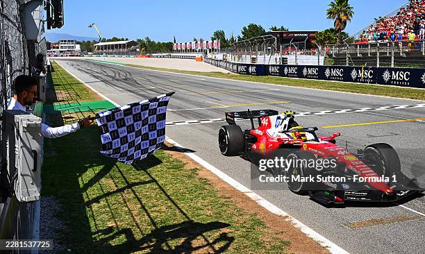 Race winner Lewis Hamilton of Great Britain driving the Scuderia Ferrari SF-26 crosses the line as Novak Djokovic waves the chequered flag during the...