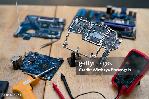 Electronics repair technician desktop with various computer components and circuit boards, using soldering iron and multimeter for precise assembly and maintenance tasks Electronics repair technician desktop with various computer components and circuit boards, using soldering iron and multimeter for precise assembly and maintenance tasks