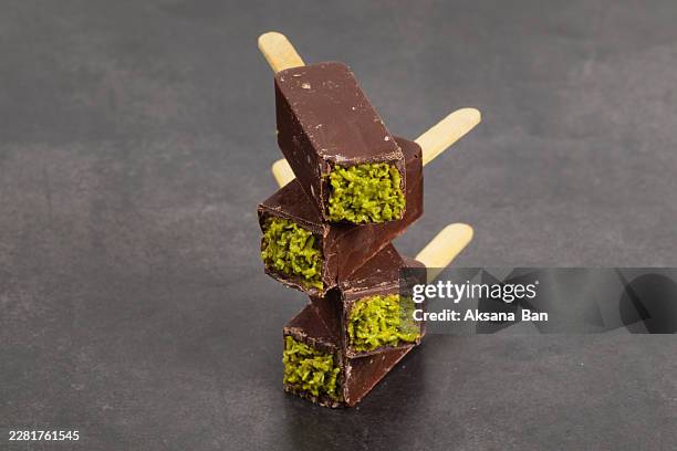 dubai chocolate dessert with crispy kataifi dough and pistachio paste. on a wooden stick. dark background. - kataifi stock pictures, royalty-free photos & images