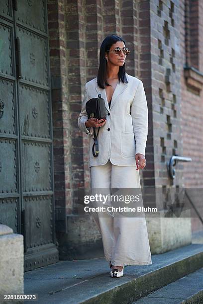 Miriam Nehring is seen wearing a light beige tailored blazer and matching wide-leg trousers by Filippa K, paired with a black Ferragamo shoulder bag...
