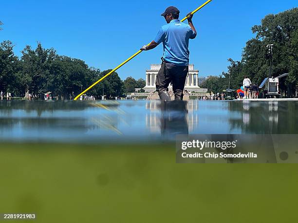 National Park Service employee uses a vacuum pump to clean algae off the bottom of the newly repainted Lincoln Memorial Reflecting Pool on the...