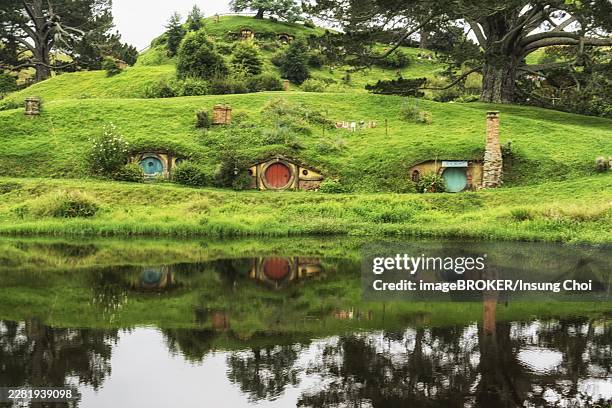hobbit holes in hobbiton movie set reflecting in a small lake. taken in new zealand - film set stock pictures, royalty-free photos & images
