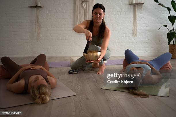 yoga instructor playing singing bowl for meditation class. - zelfverbetering stockfoto's en -beelden