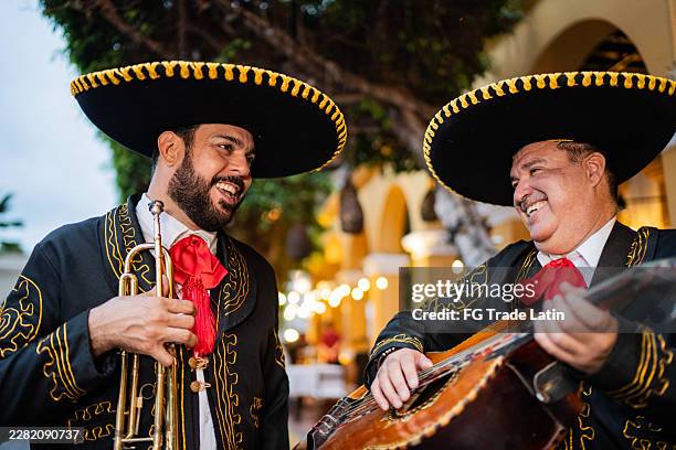 mariachi friends talking while playing musical instruments on the city - latin music stock pictures, royalty-free photos & images