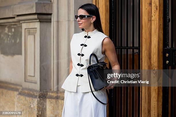 Zina Charkoplia wears white sleeveless top and pants Uara, Armet sandals, Hermes bag, Chanel sunglasses on June 17, 2026 in Barcelona, Spain.