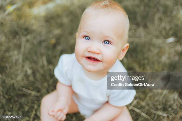 happy baby playing outdoors in green grass - stock image - baby girls stock pictures, royalty-free photos & images