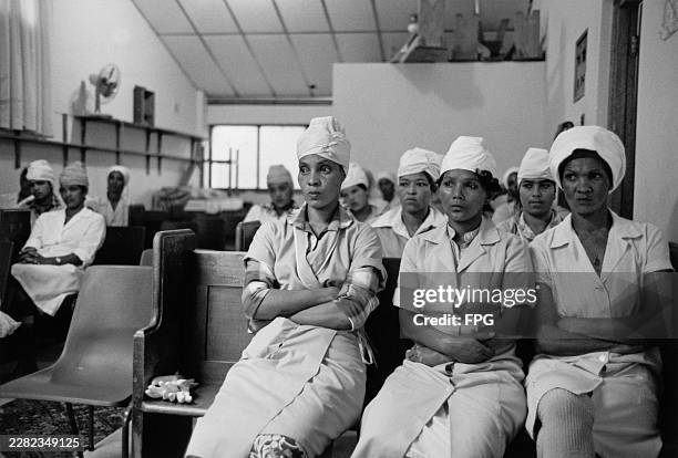 Three women sit with their arms folded during a fishery industry trade union meeting in Cape Town, South Africa, 1985.