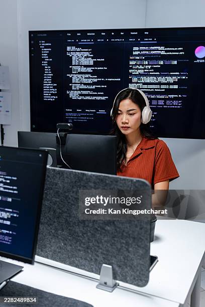asian female developer typing source code while thinking through program logic in office. - devops stock pictures, royalty-free photos & images