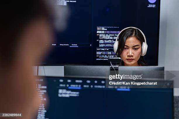 female software engineer looking at screen while typing code, working on software development while concentrating on source code at desk. - devops stock pictures, royalty-free photos & images