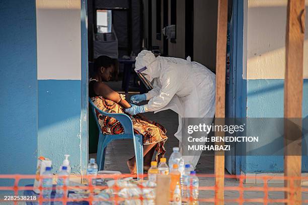 Healthcare worker takes samples from a patient suffering from Ebola virus disease at the Ebola Treatment Center of the Center Médical Évangélique ,...