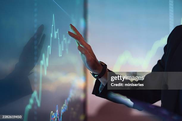 business professional interacting with stock market touchscreen display showing finance and cryptocurrency charts - volatile stock pictures, royalty-free photos & images