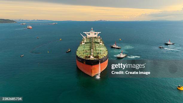aerial front view tugboat pushing and pulling oil ship tanker to loading dock on the sea for energy or power business logistics import export shipping or freight transportation. - tanker ship stock pictures, royalty-free photos & images