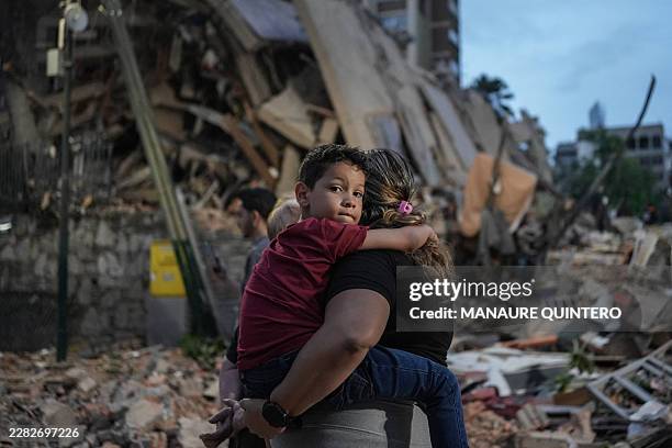 People walk past a collapsed building following an earthquake in Caracas on June 25, 2026. Powerful twin earthquakes have killed 32 people and...