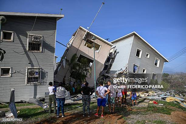 People stand before damaged homes following an earthquake in Catia La Mar, La Guaira state, some 30km north-west of Caracas, on June 25, 2026. A twin...