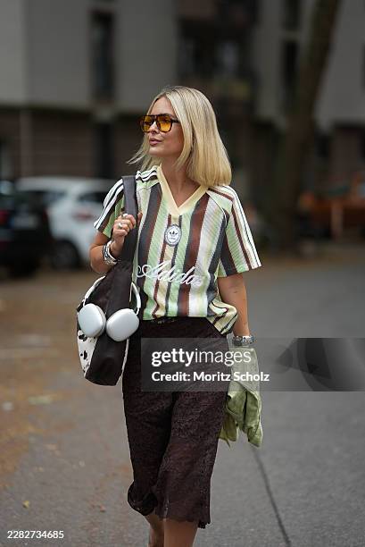 Julia Kammerer is seen wearing a green white brown striped football jersey from Adidas; a light pistachio check shirt from NA-KD; dark brown lace...