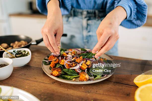 hands adding chopped walnuts to healthy salad - salad bowl stock pictures, royalty-free photos & images