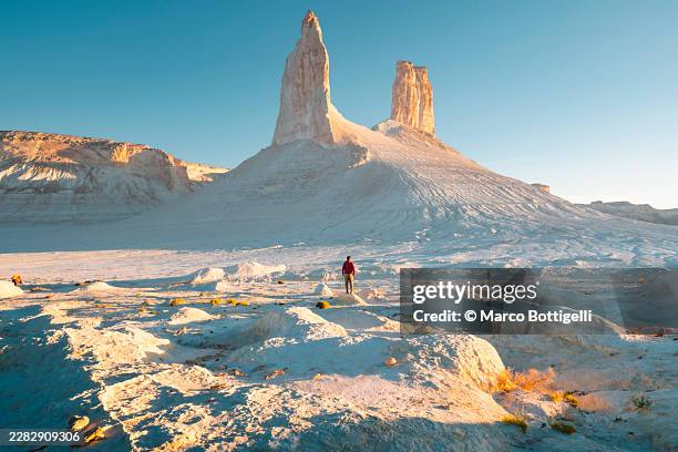 traveller walking toward twin chalk towers at sunrise, mangystau, kazakhstan - salt flat stock pictures, royalty-free photos & images