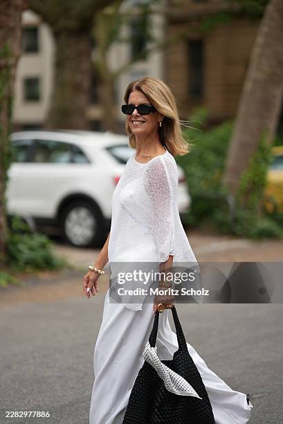 Yvonne Schuppler-Kammerer is seen wearing an asymmetrical white sheer knit cape from Ibiza; a white lace-trimmed top from Bershka; white wide leg...