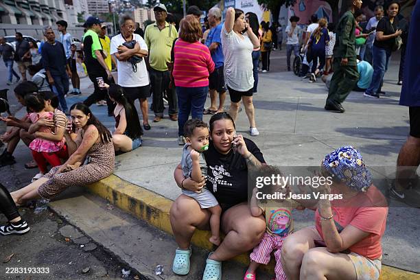 Evacuated people speak by phone waiting at Parque Central urban development complex after a magnitude 7.2 earthquake struck Venezuela and other...