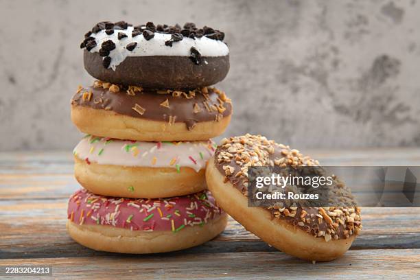 assorted colorful donuts on rustic blue wooden table - tubules stock pictures, royalty-free photos & images