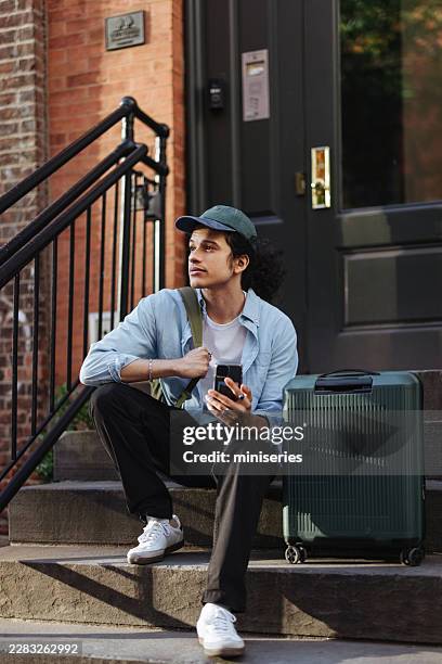 young tourist with suitcase waiting on new york city brownstone steps while exploring urban streets - looking around stock pictures, royalty-free photos & images