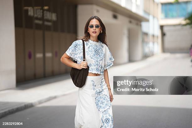 Amanda Mühle is seen wearing a white cropped blouse with blue embroidered motifs, wide short sleeves and scalloped edges from Sézane; a white high...