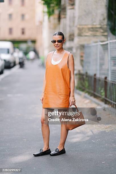 Veronica Ferraro wearing a sleeveless tan leather mini dress, a white tank top, black loafers, sunglasses is seen outside Tod's presentation during...