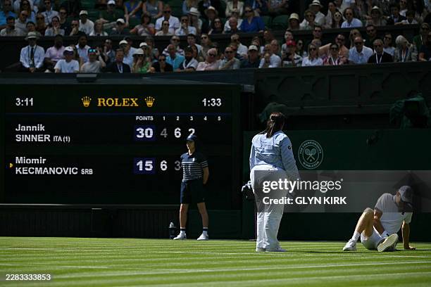 The umpire checks on Italy's Jannik Sinner after slipping during his men's singles first round tennis match against Serbia's Miomir Kecmanovic, on...