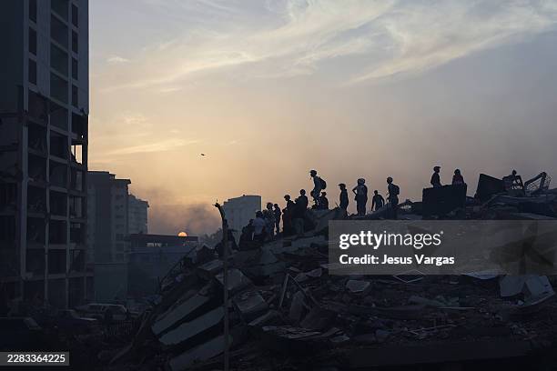 People search for victims amid debris of demolished buildings as rescue efforts continue after a magnitude 7.2 earthquake struck Venezuela and other...