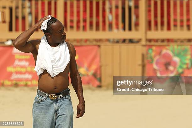 Man wipes down his head with a towel as he heads to the cool water of Lake Michigan to get some relief from the heat at Margaret T. Burroughs Beach...