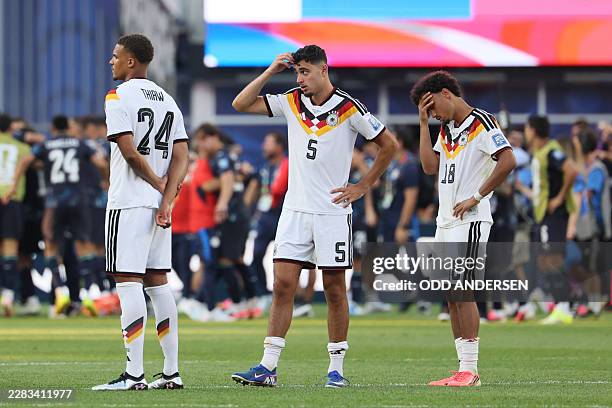 Germany's defender Malick Thiaw, defender Aleksandar Pavlovic, and defender Nathaniel Brown react after losing the penalty shootout of the 2026 World...