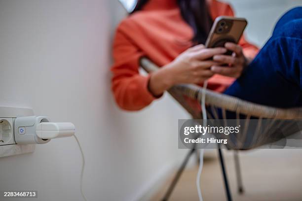 smart plug connects to device while a woman uses her phone indoors - plugging in stock pictures, royalty-free photos & images