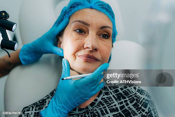 senior adult woman receiving facial assessment before cosmetic rejuvenation treatment - face lift stock pictures, royalty-free photos & images