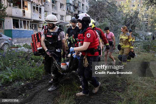 Members of the Ukrainian Red Cross carry an injured resident from a collapsed residential building after a drone and missile attack by Russian forces...