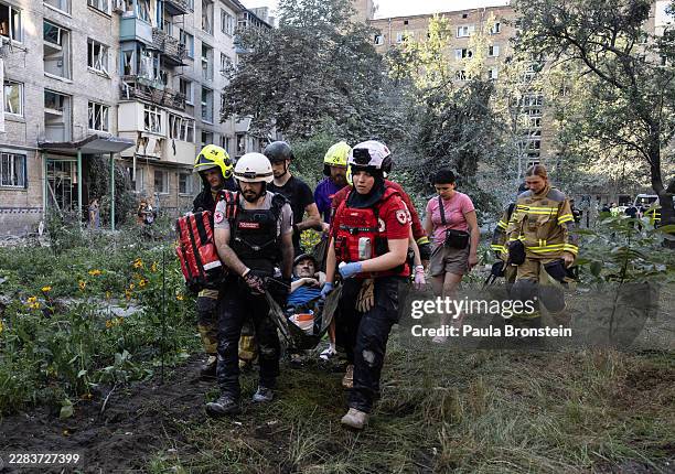 Members of the Ukrainian Red Cross carry an injured resident from a collapsed residential building after a drone and missile attack by Russian forces...