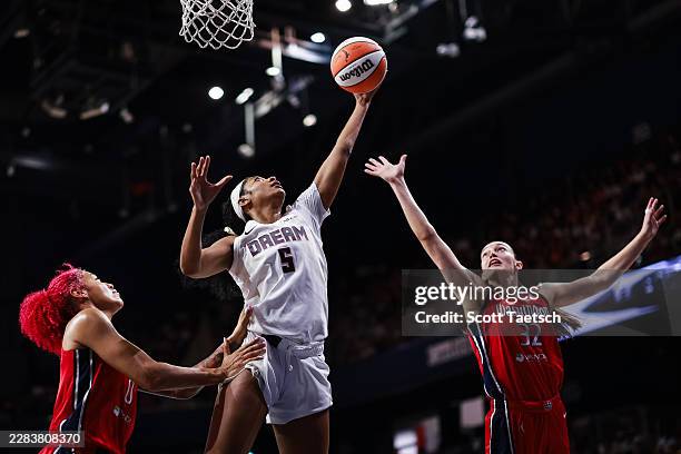 Angel Reese of the Atlanta Dream grabs a rebound against Shakira Austin and Angela Dugalic of the Washington Mystics during the first half of the...