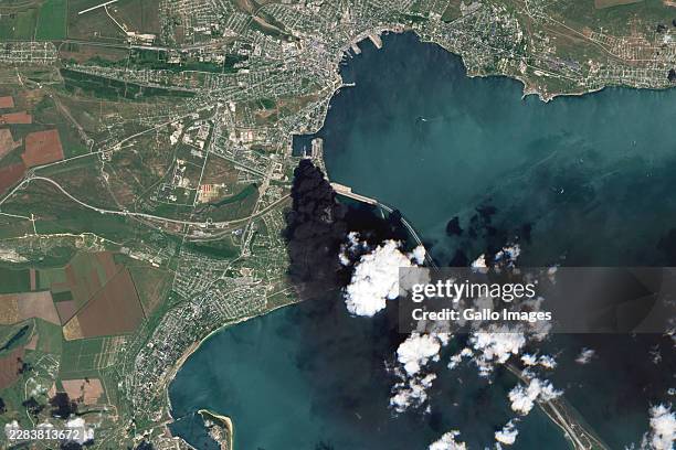 Satellite view of burning storage tanks and heavy smoke following attacks in Kerch on June 21, 2026. The image shows oil storage tanks emitting dark...
