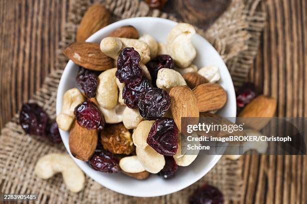 portion of mixed nuts and fruits (trail mix) on wooden background - trail mix stock pictures, royalty-free photos & images