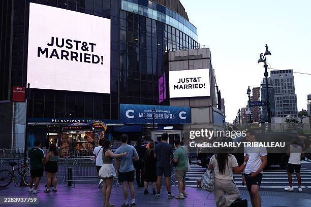 People watch giant screens showing the message "JUST&T MARRIED!" outside Madison Square Garden, the reported venue for the wedding celebrations of...